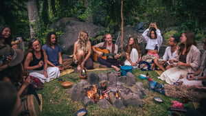 Cacao ceremony circle by the fire as a facilitator plays guitar with cups of ceremonial cacao